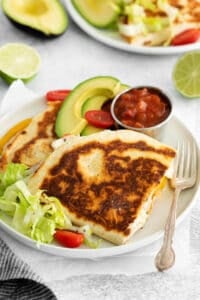 quesadillas on a plate with avocado and tomatoes.