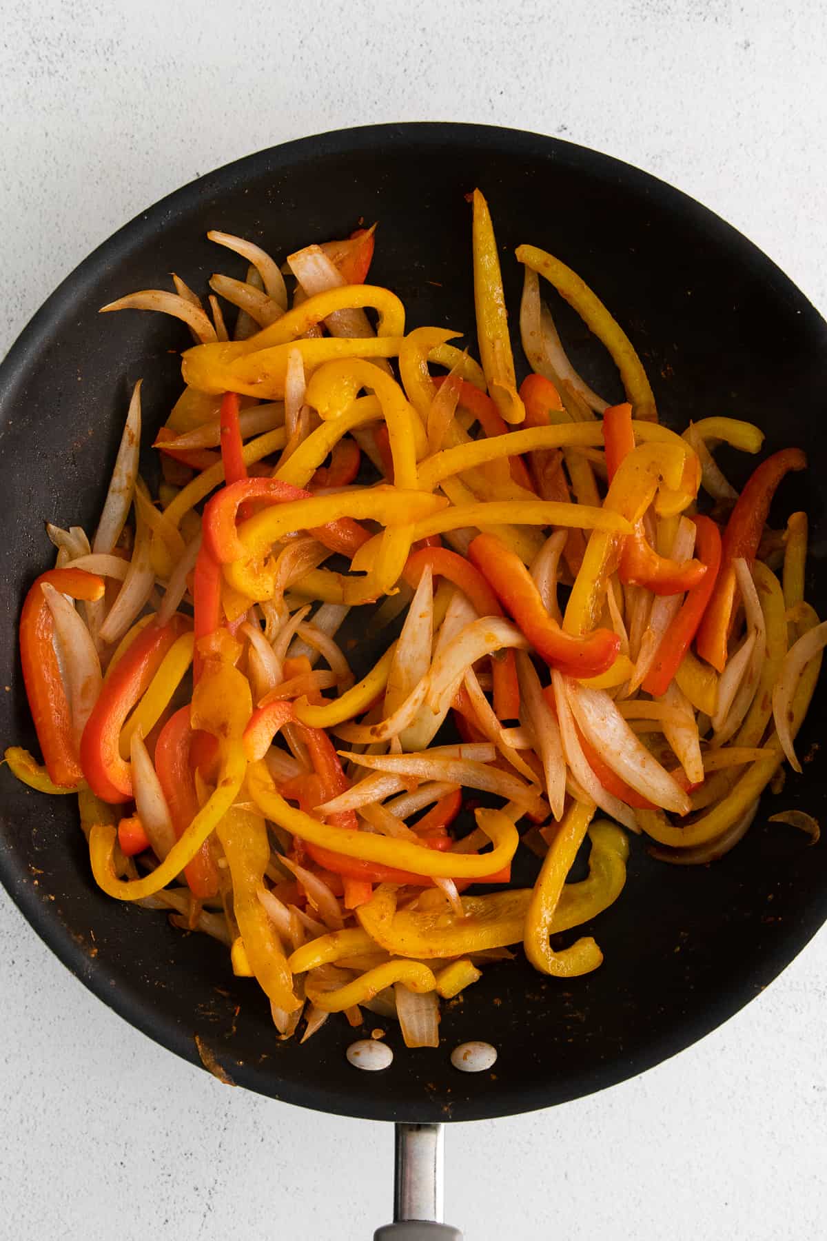 Sauteed onions and bell peppers in a skillet.