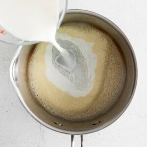 a person pouring milk into a pan.