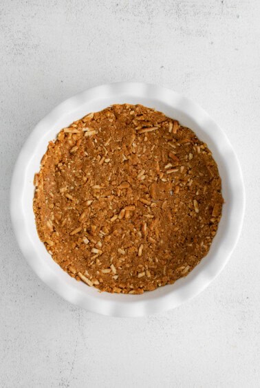 A white dish filled with granola and strawberry cream cheese pie on a white background.