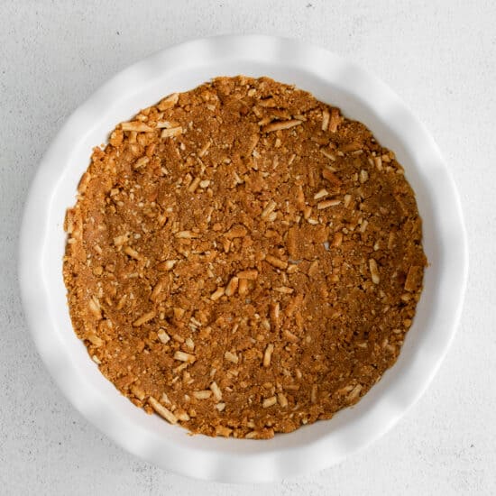A white dish filled with granola and strawberry cream cheese pie on a white background.