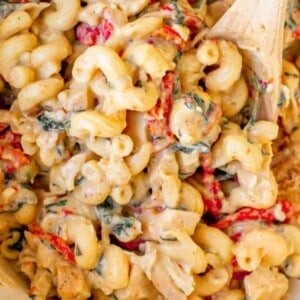 A Tuscan chicken mac and cheese dish, complete with a wooden spoon.