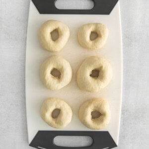 uncooked bagels on cutting board.