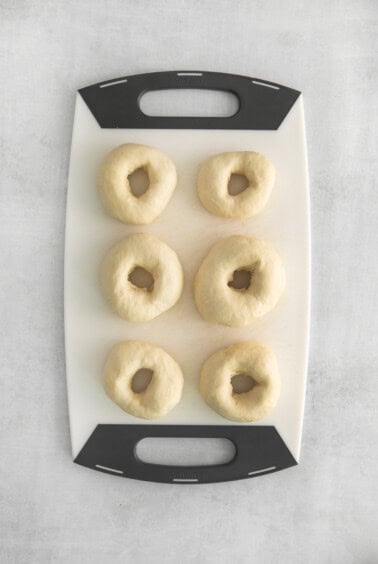 uncooked bagels on cutting board.