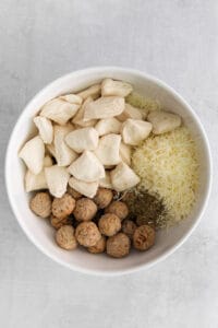 a white bowl filled with cheese, mushrooms, and other ingredients.