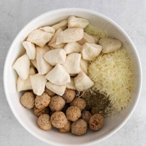 a white bowl filled with cheese, mushrooms, and other ingredients.