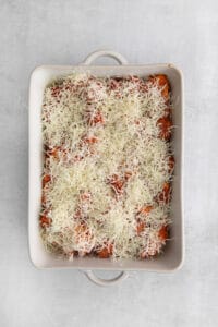 a casserole dish topped with cheese and tomatoes.
