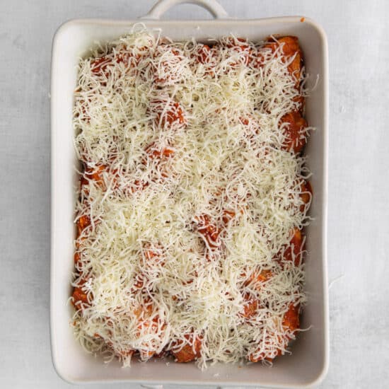 a casserole dish topped with cheese and tomatoes.