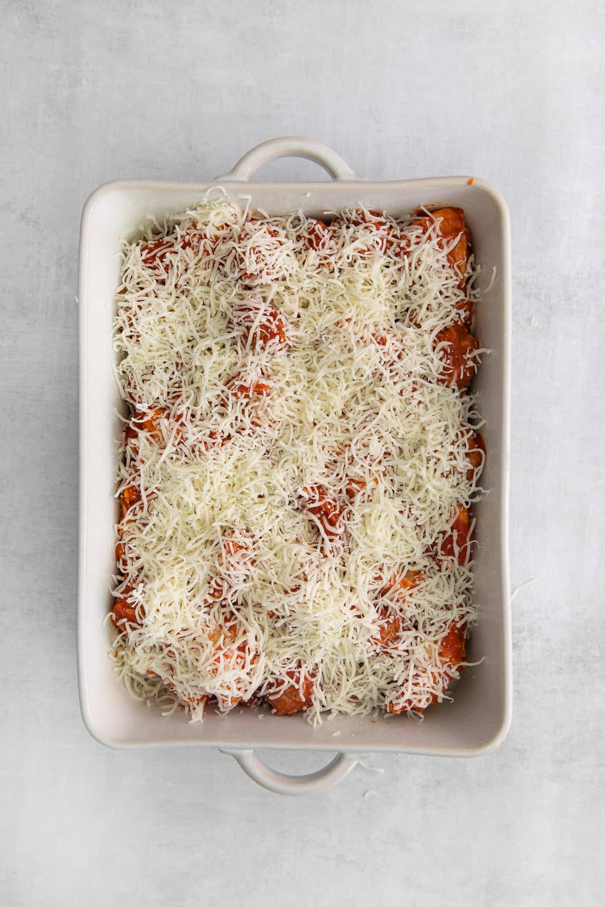 Bubble bake covered in shredded cheese in a casserole dish.