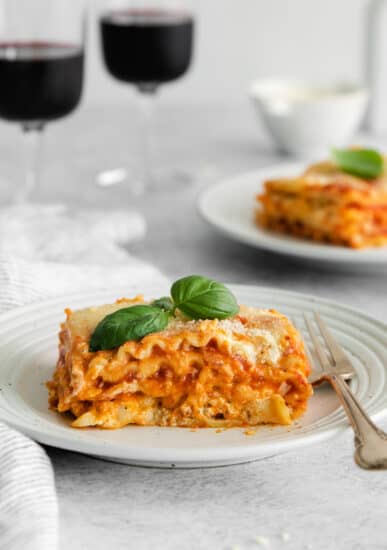 slice of cheese lasagna with wine glasses.