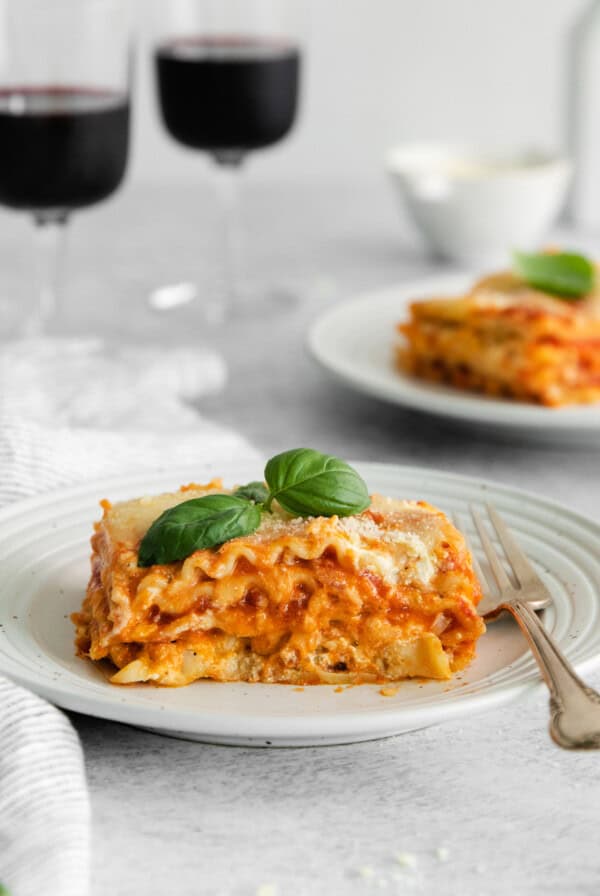 slice of cheese lasagna with wine glasses.