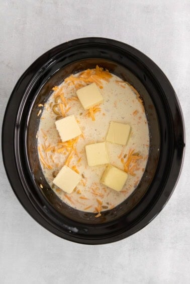 a crock pot filled with cheese and butter.
