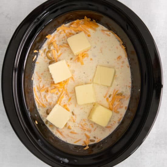 a crock pot filled with cheese and butter.