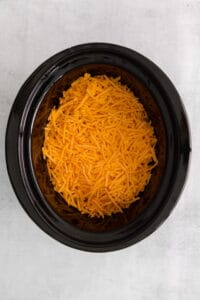 shredded cheese in a black crock pot.