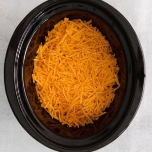 shredded cheese in a black crock pot.