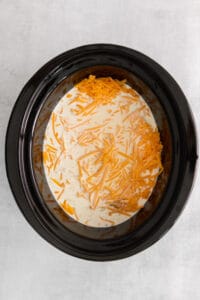 a crock pot filled with cheese and carrots.