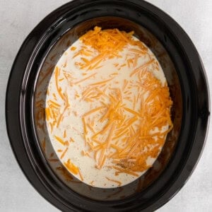 a crock pot filled with cheese and carrots.