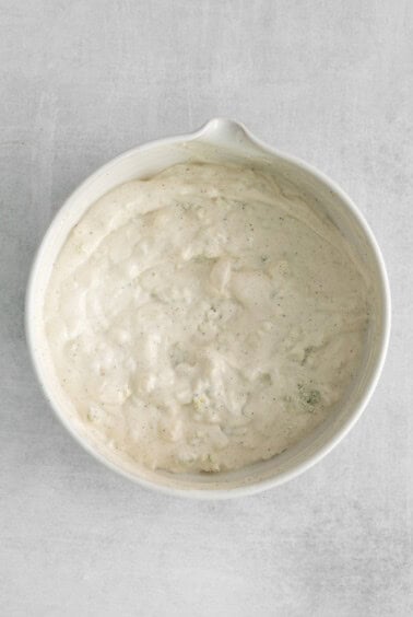 a white bowl filled with a white sauce.