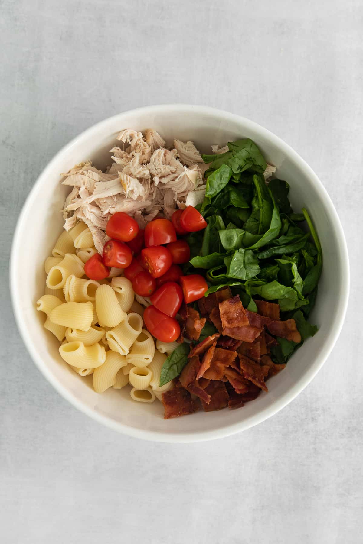Ingredients for gorgonzola chicken pasta salad in a bowl.