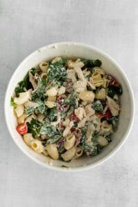 chicken kale pasta salad in a white bowl.