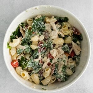 chicken kale pasta salad in a white bowl.