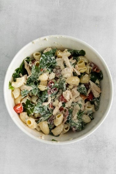 chicken kale pasta salad in a white bowl.