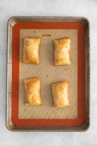 a baking sheet with four squares of pastries on it.