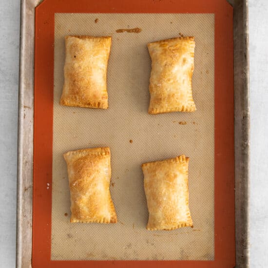a baking sheet with four squares of pastries on it.
