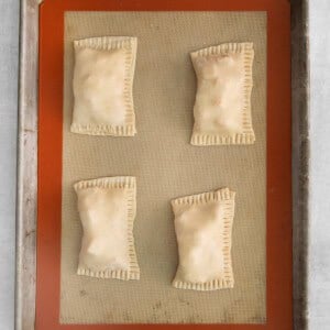 four squares of puff pastry on a baking sheet.