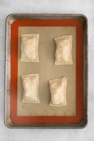 four squares of puff pastry on a baking sheet.