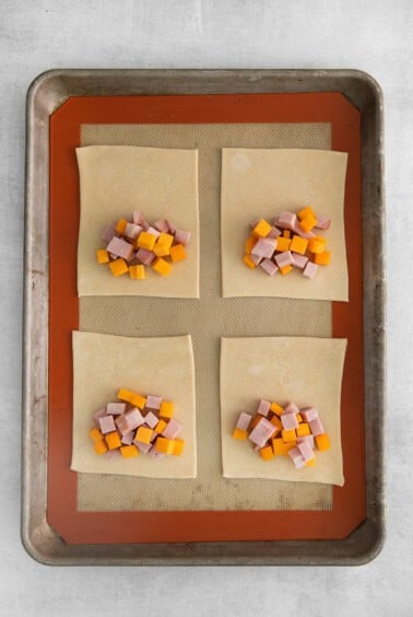 four squares of ham and cheese on a baking sheet.