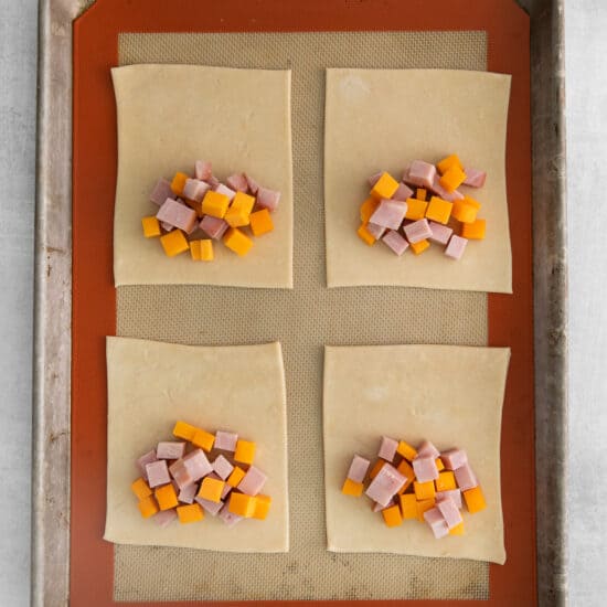 four squares of ham and cheese on a baking sheet.
