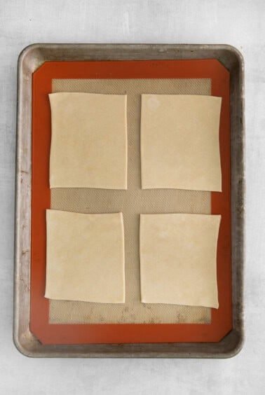 four squares of dough on a baking sheet.