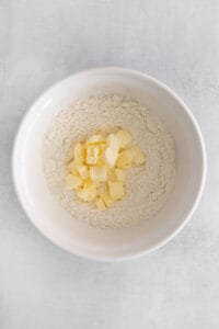 a white bowl with flour and butter in it.