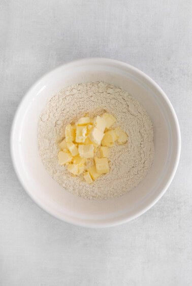 a white bowl with flour and butter in it.