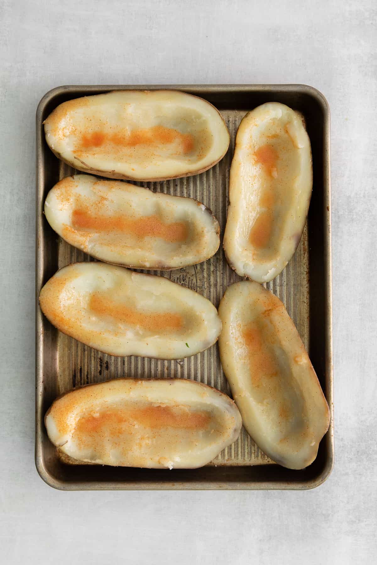 Hallowed out potato skins on a baking sheet. 