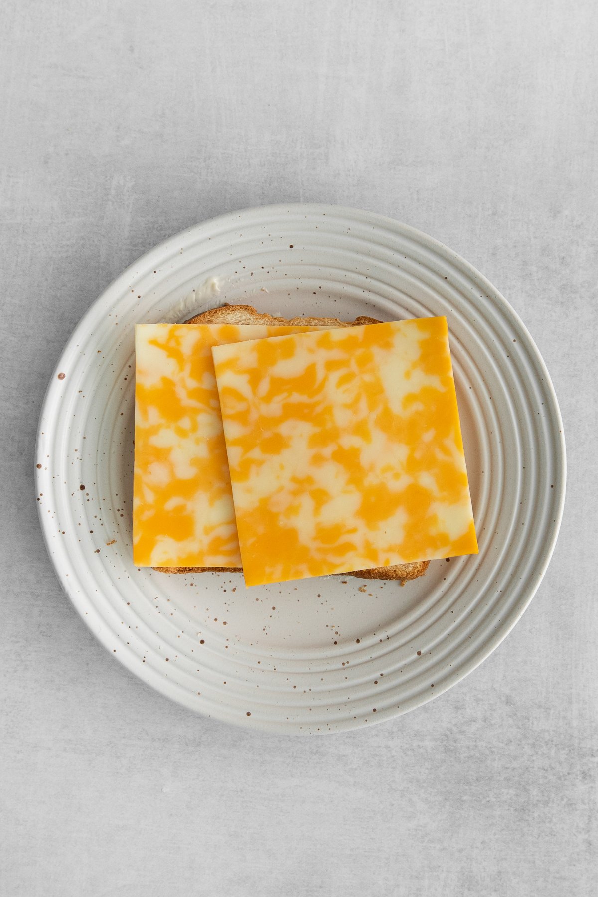 Two slices of colby cheese on a slice of bread.