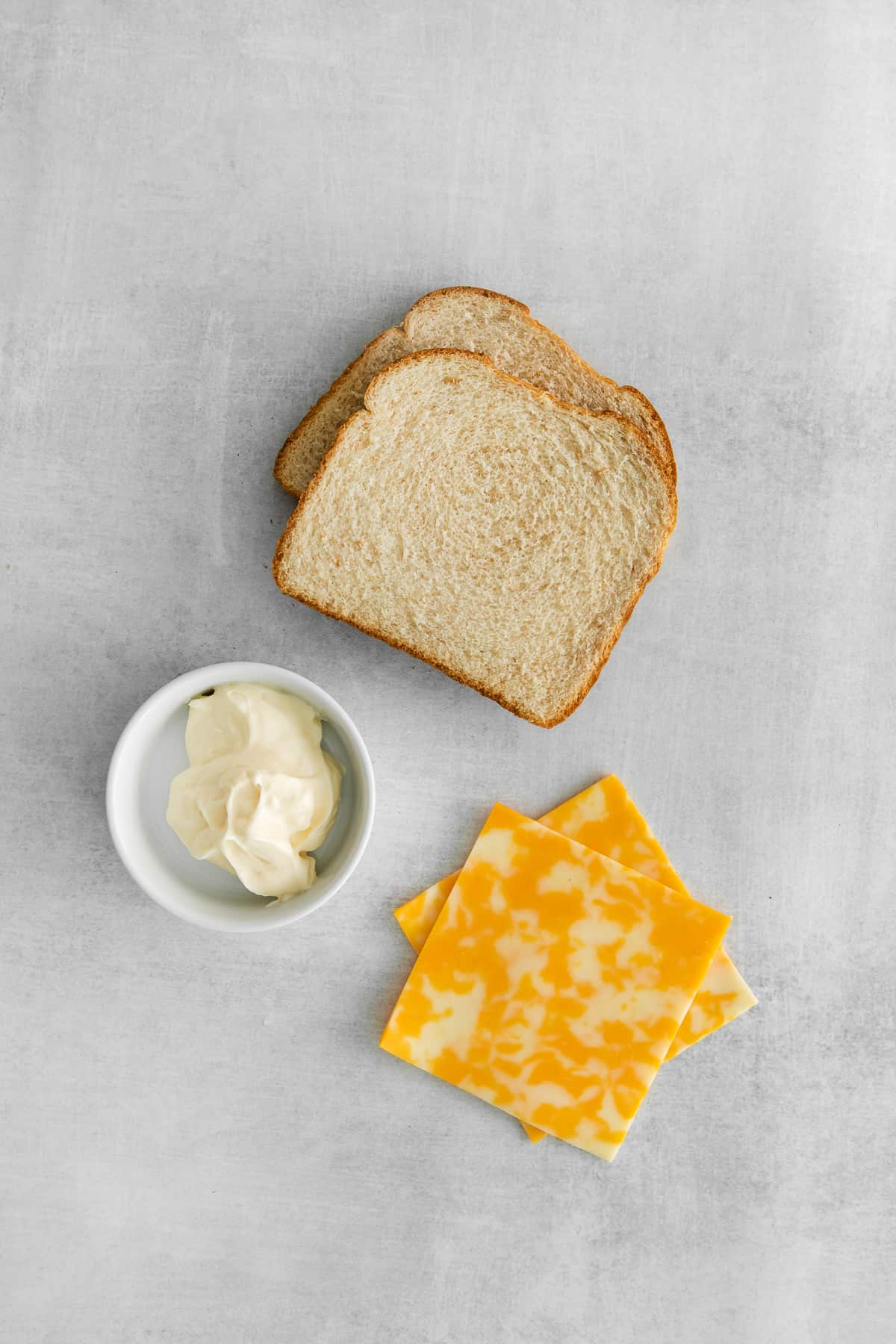 Ingredients for grilled cheese with mayo on a plate.