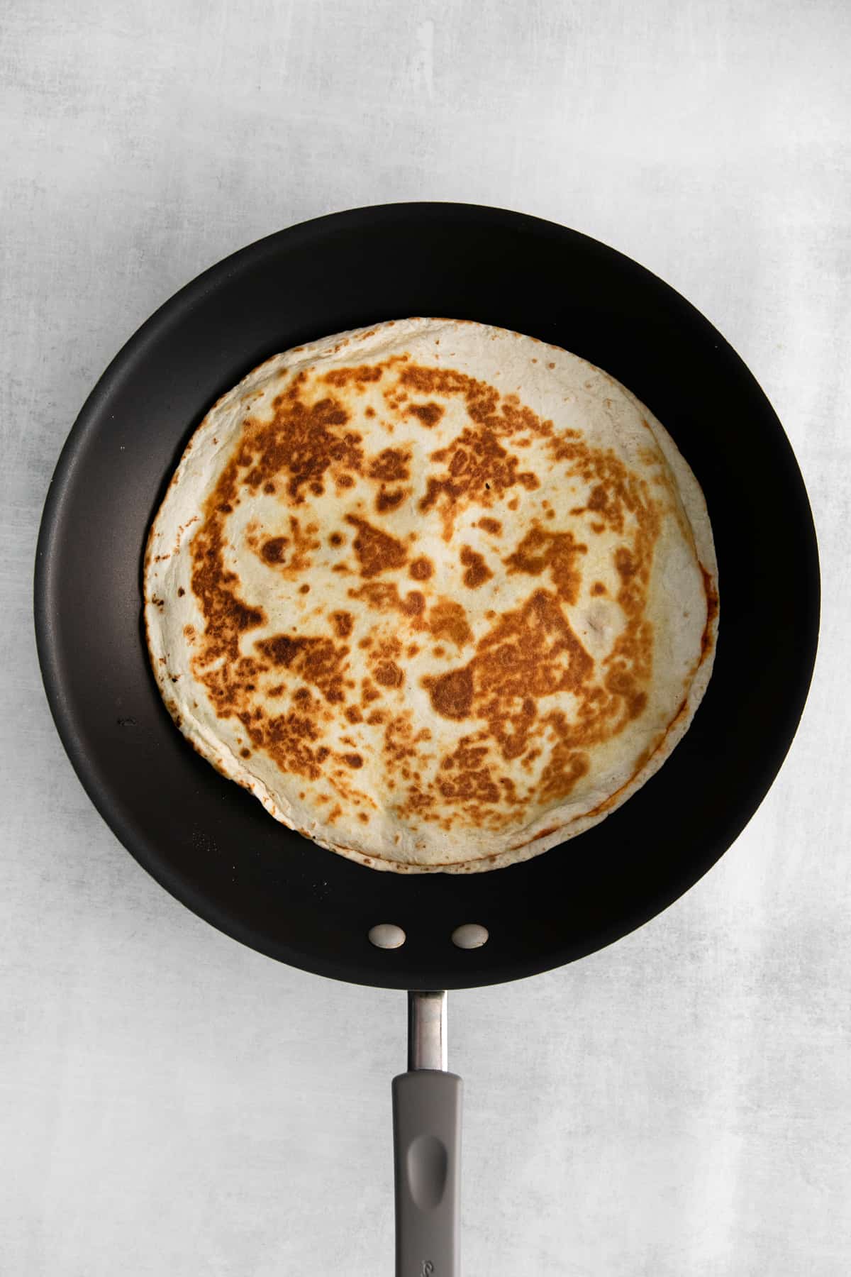 Cooking a quesadilla in a skillet pan.