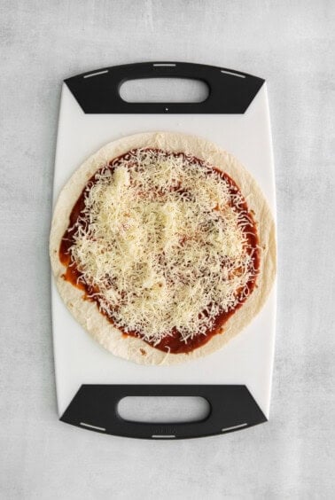 Tortilla topped with sauce and mozzarella cheese.