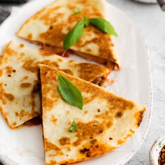 A sliced quesadilla topped with fresh basil.