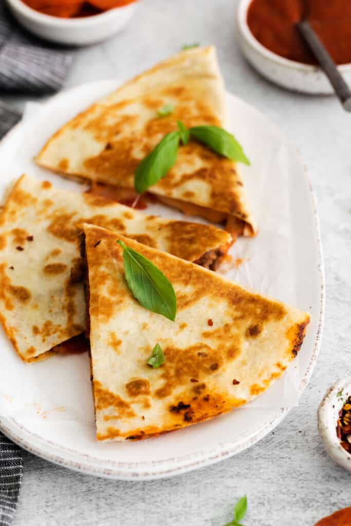 A sliced quesadilla topped with fresh basil.