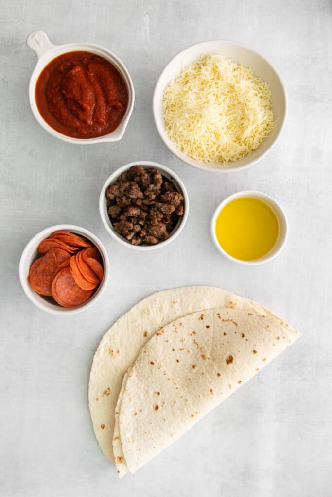 Ingredients for pizza quesadillas in small bowls.