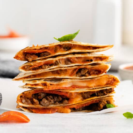 A pizza quesadilla stacked on a plate.