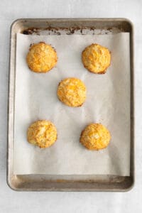 four cheesy biscuits on a baking sheet.