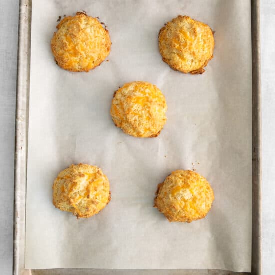 four cheesy biscuits on a baking sheet.