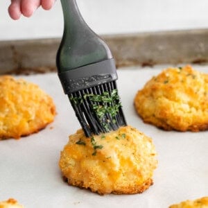 a person is sprinkling cheese on a baking sheet.