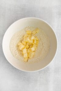 a bowl of flour and butter in a white bowl.
