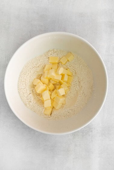 a bowl of flour and butter in a white bowl.