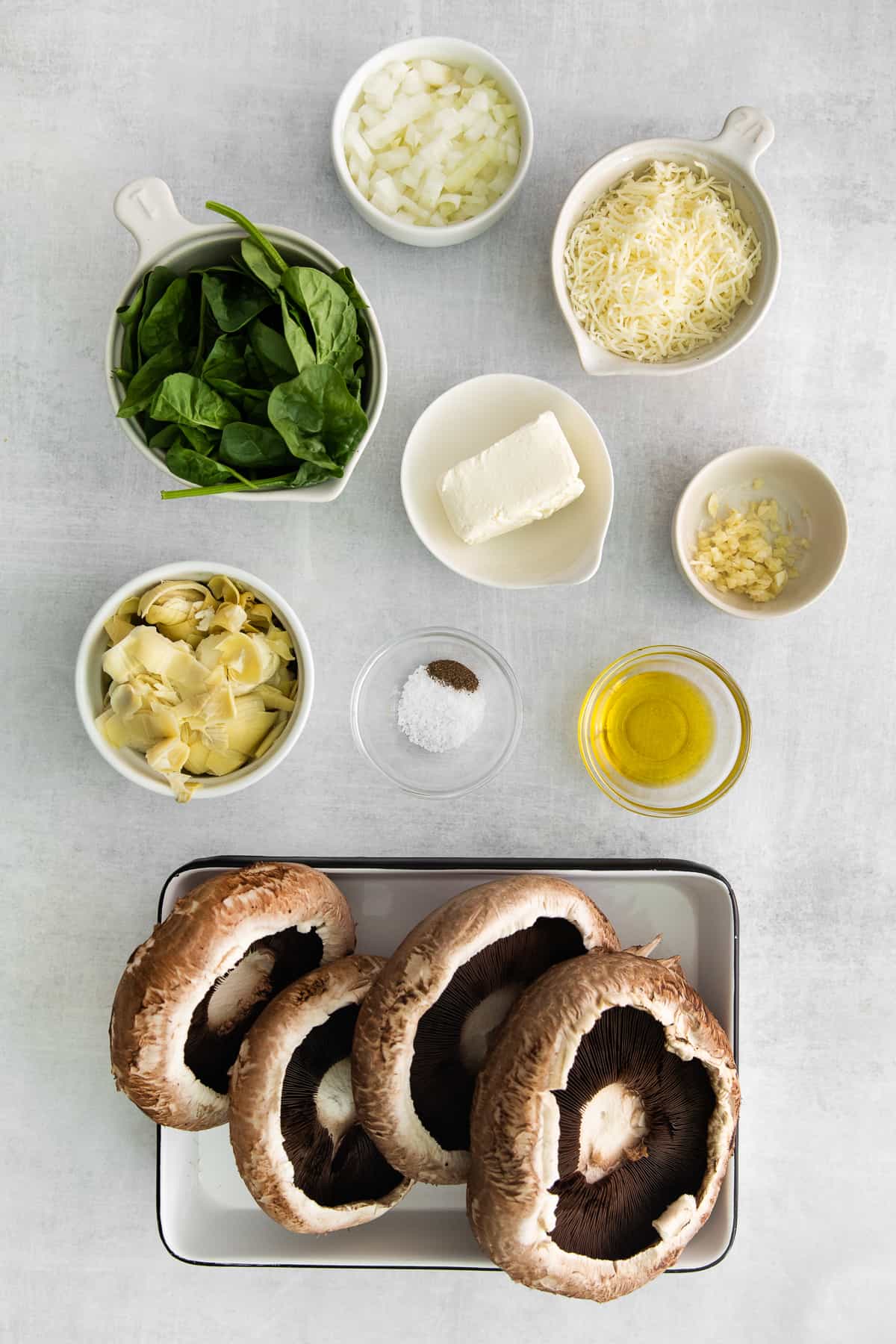 All of the ingredients for spinach artichoke stuffed mushrooms in small bowls. 